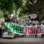 Group of activists marching for climate justice in Maastricht with banners and signs.